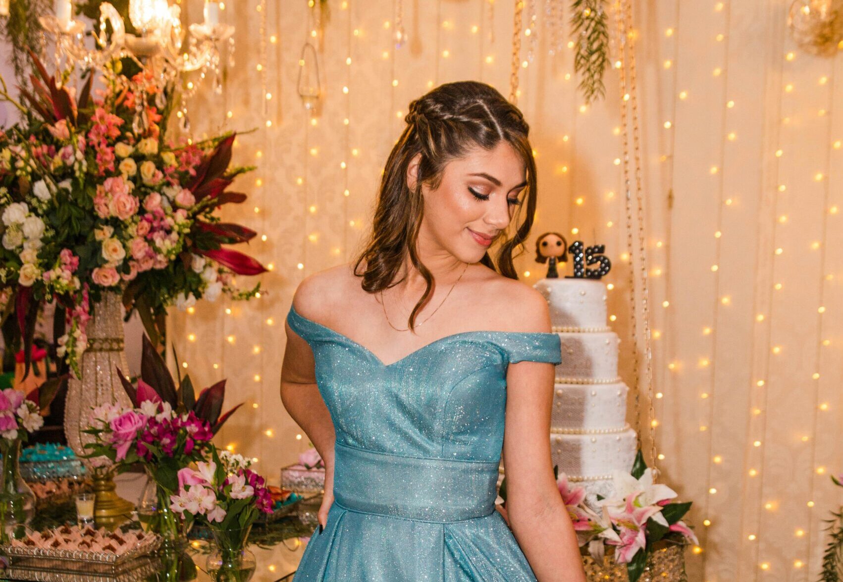 An elegantly dressed woman celebrating her birthday party with a beautifully decorated backdrop.